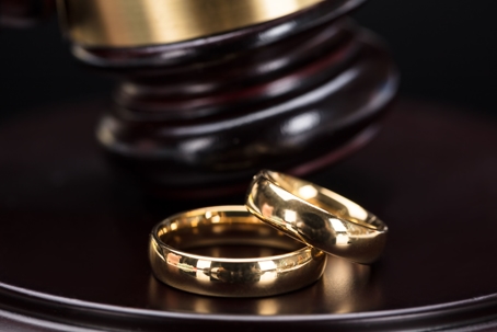 Two gold wedding bands sitting on top of a gavel