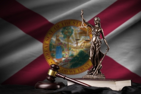Florida US state flag with statue of lady justice, constitution and judge hammer on black drapery. Concept of judgement and punishment