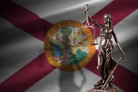 Florida US state flag with statue of lady justice and judicial scales in dark room. Concept of judgement and punishment, background for jury topics