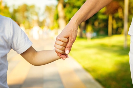 Close up of hands of a child and parent on the walk at the local park